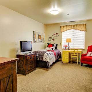 A cozy bedroom with a single bed, television, and bright furnishings.
