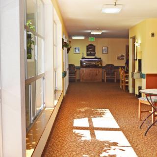 A sunlit hallway with a seating area and carpeted floor.