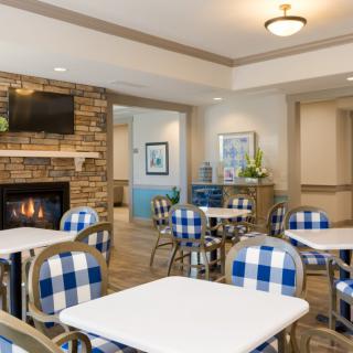 A cozy cafe interior with blue and white checkered chairs, a fireplace, and modern decor.