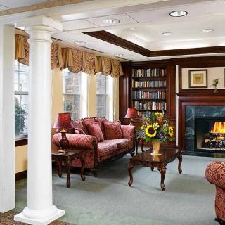 A cozy living room with a fireplace, bookshelves, and traditional decor.