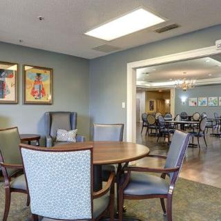 A spacious dining area with wooden tables and chairs, decorated with artwork and illuminated by soft lighting.