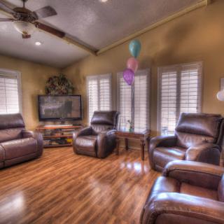 A cozy living room with leather recliners, a television, and festive balloons.
