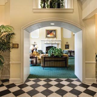 A welcoming lobby area featuring an archway, checkered flooring, and cozy seating around a fireplace.