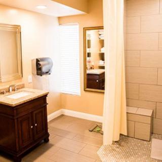 A spacious bathroom featuring a vanity with a mirror, a shower with a curtain, and tiled flooring.