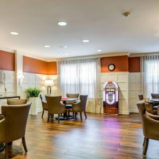 A cozy lounge area featuring comfortable chairs and tables, with warm lighting and a jukebox for ambiance.