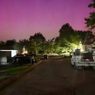 A serene night scene showcasing a quiet street illuminated by soft lights under a vibrant purple sky.