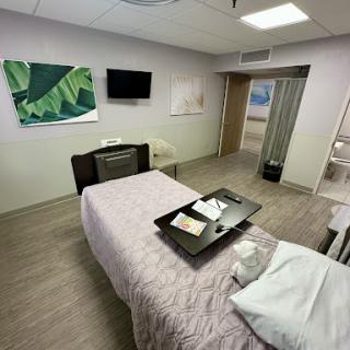 A modern and clean hospital patient room equipped with a bed, TV, and decorative artwork.