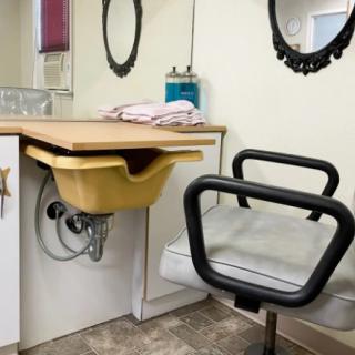 A cozy hair salon setup with a sink, mirror, and styling chair.