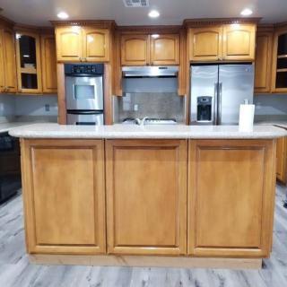 A modern kitchen with wooden cabinets and a central island, featuring appliances and a spacious countertop.