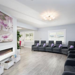 A modern waiting room with comfortable recliner chairs and contemporary artwork.
