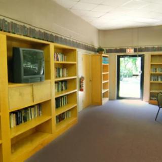 A library interior with bookshelves and a television by the door.