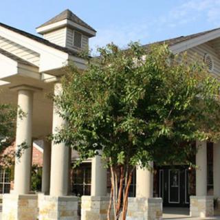 A building with prominent columns and a tree in front.