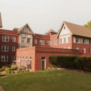 A brick residential building with multiple stories and a well-maintained lawn.