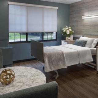A modern and comfortable hospital room with a bed, decorated interior, and large window.