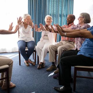 A group of seniors engaging in a seated exercise activity indoors.