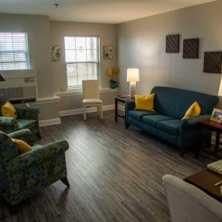 A cozy living room with sofas, chairs, and warm lighting.