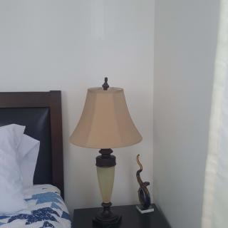 A cozy bedroom corner with a stylish table lamp on a nightstand.