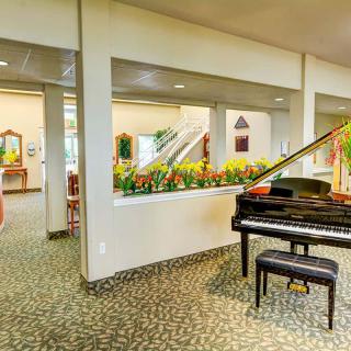 A spacious interior lobby area featuring a grand piano and decorative plants.