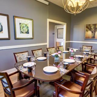 A well-decorated dining room with a large table set for a meal, featuring artwork and a chandelier.