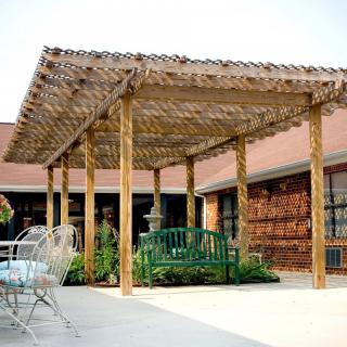 A wooden pergola on a patio with outdoor seating and a garden bench.