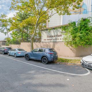 Cars parked along a street beside a building on a sunny day.
