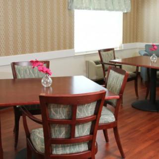 A cozy dining area with wooden tables and chairs, adorned with small flower decorations.