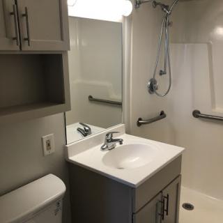 A modern bathroom featuring a sink, toilet, shower, and storage cabinets.
