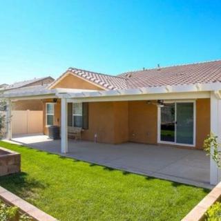 A sunny backyard with a patio and well-maintained lawn.
