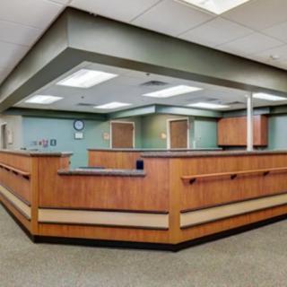 Spacious office reception area with wooden counter and modern lighting.