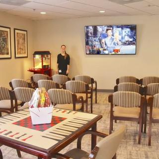 A comfortable waiting room with rows of chairs, a table with a basket, a television on the wall, and a popcorn machine in the corner.