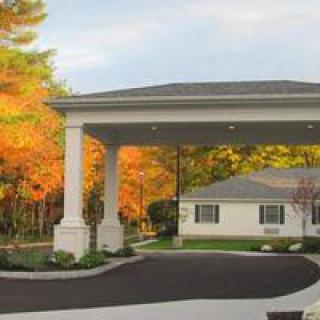 A house with a covered entrance and autumn trees in the background.