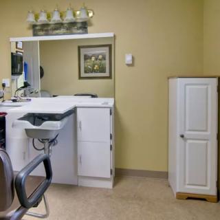 An interior view of a hair salon with a chair, sink, and cabinet.
