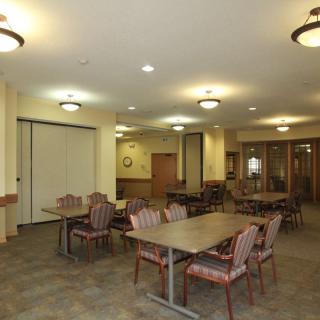 A spacious dining area with arranged tables and chairs, well-lit by ceiling fixtures.