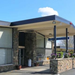 A modern building entrance with stone walls and a flat roof on a sunny day.