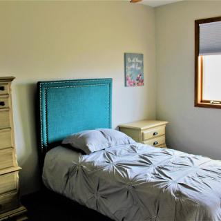 A cozy bedroom with a teal headboard and cream-colored furniture.