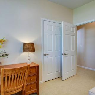 A cozy bedroom with a wooden desk, chair, and an open closet.