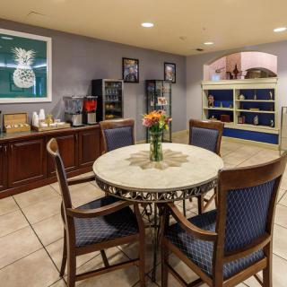 Cozy dining area with a round table and chairs, featuring a vase of flowers, surrounded by cabinets and a beverage station.