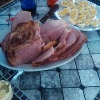 A platter of sliced ham served alongside other snacks.
