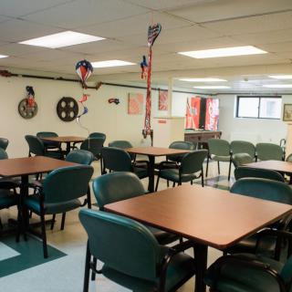 An empty dining area with tables and chairs, decorated with various hanging items.