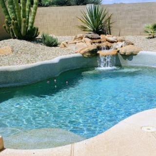 A serene backyard oasis featuring a sparkling swimming pool and natural landscaping.