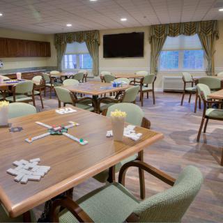 Cozy dining room with neatly arranged tables and chairs, adorned with large windows and curtains.