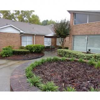 A brick house with landscaped garden and pathway in the yard.