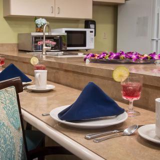 A neatly arranged table setting in a kitchen with folded napkins and drinks garnished with lemon slices.