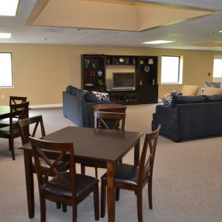 A spacious basement living area featuring comfortable seating and a table setup.