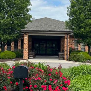 A building entrance surrounded by greenery and vibrant flowers.