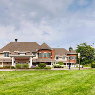 A residential building with a large lawn and cloudy sky.