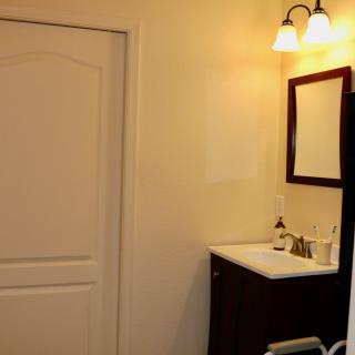 A bathroom interior featuring a sink with a mirror and overhead lighting.