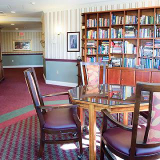 A cozy library interior with bookshelves, a table, and chairs.
