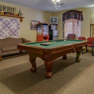 A cozy indoor game room featuring a pool table, sofa, and chairs.