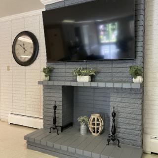 A modern living room setup featuring a large flat-screen TV mounted above a stylish gray brick fireplace.